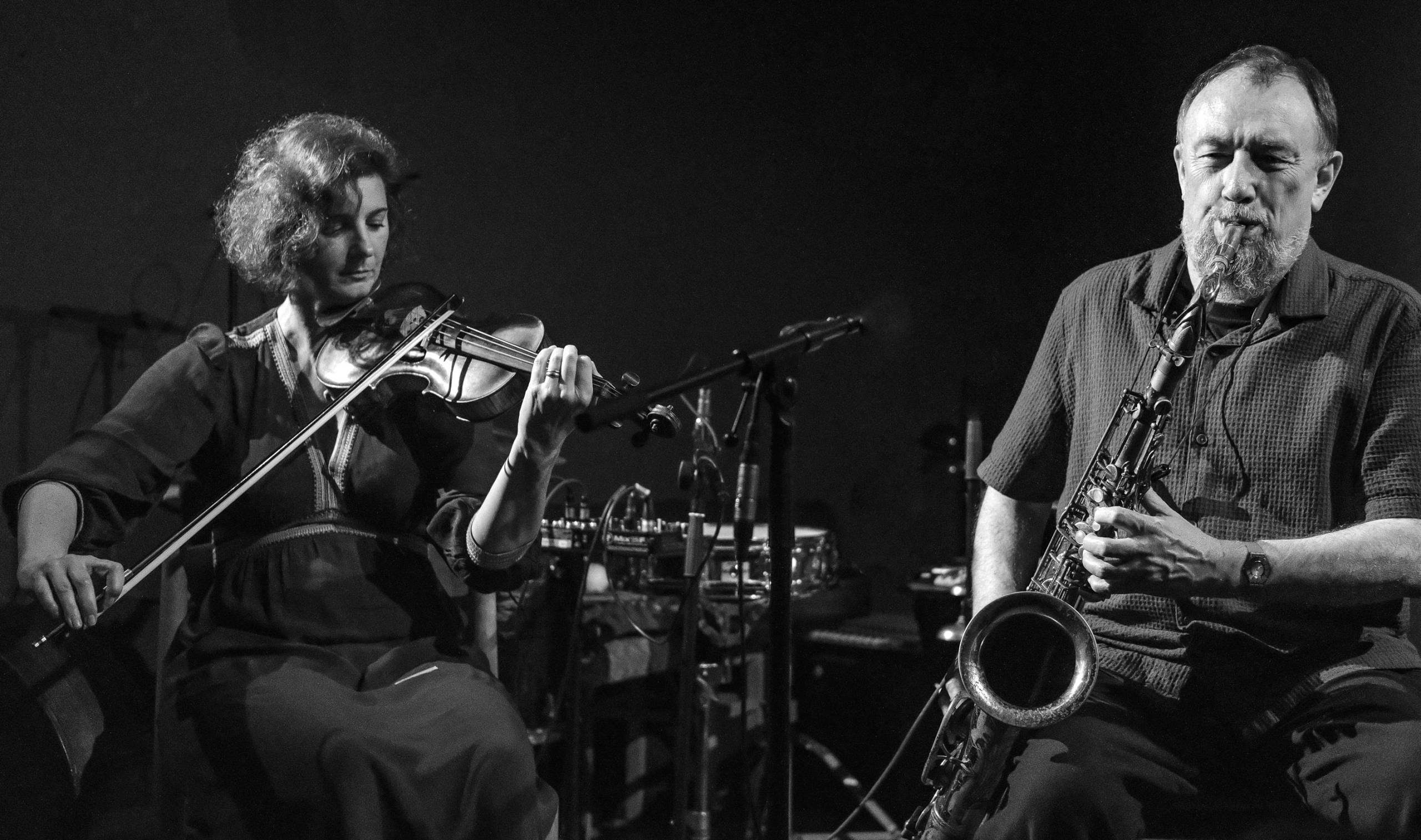 A violinist and saxophonist performing a concert.